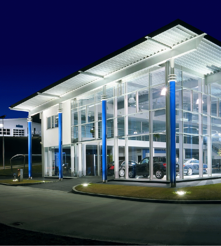 Modern glass building with cars inside illuminated at night