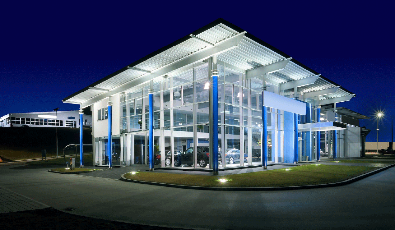 Modern glass building with cars inside illuminated at night