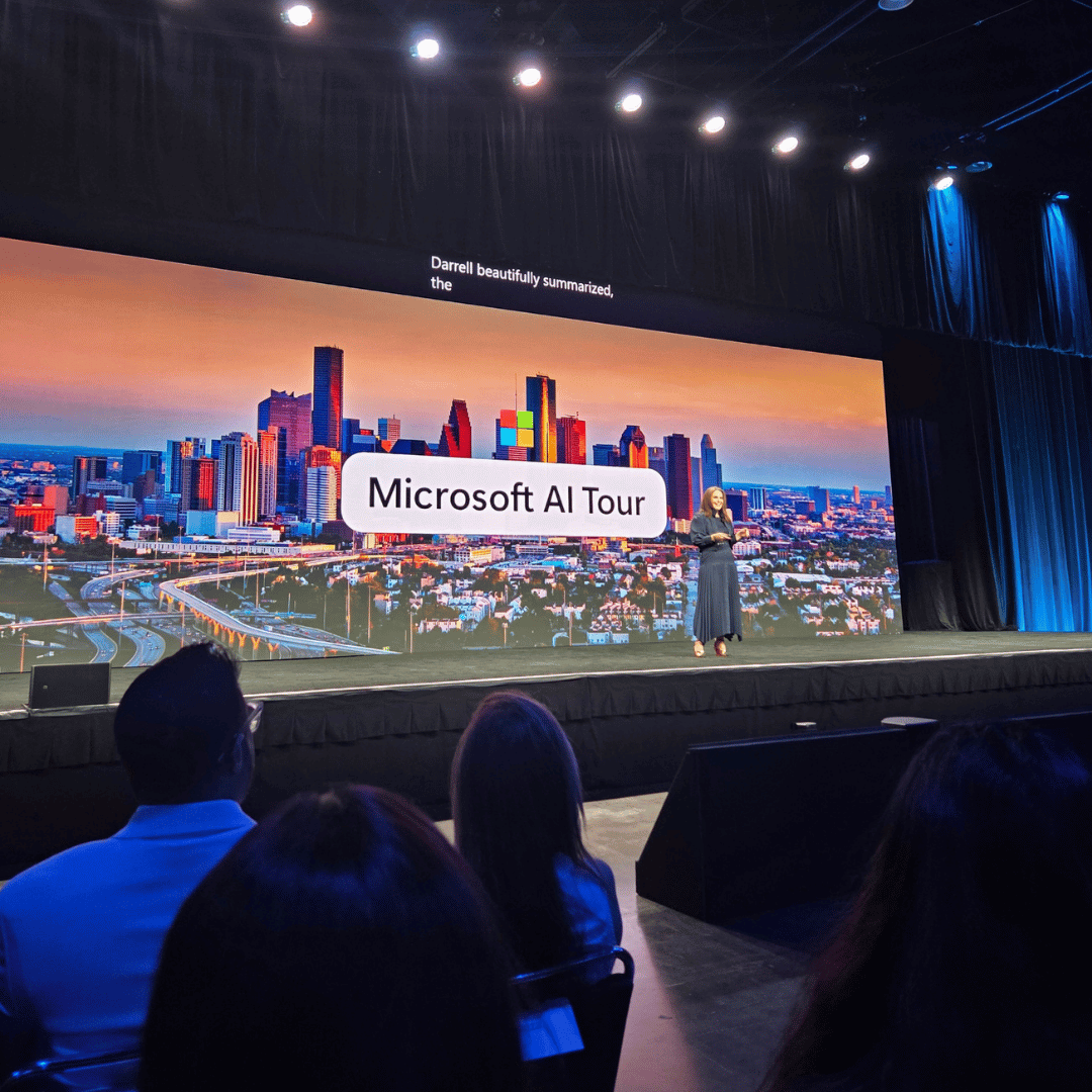 Speaker standing on stage in front of a large screen showing the Houston city skyline with the text 'Microsoft AI Tour'